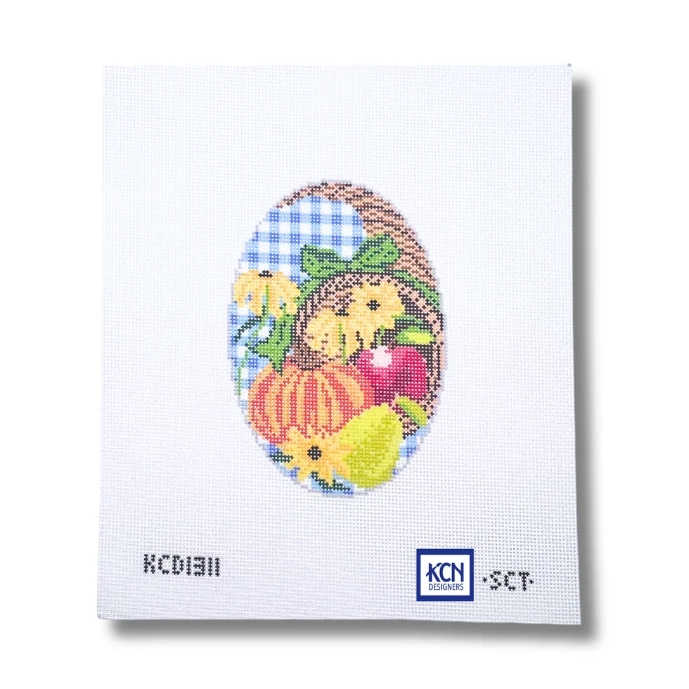 Needlepoint Canvas with autumn cornucopia painted on it filled with a pumpkin and fruit with a plaid background.