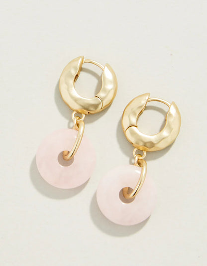 Gold hoop earrings with pink circular charms on a light gray background