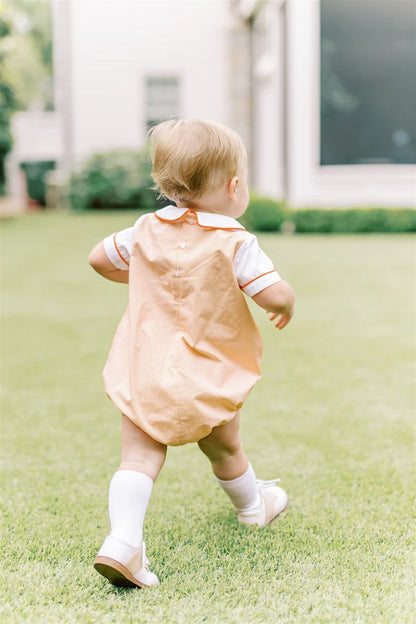 Baby in a peach dress walking on grass
