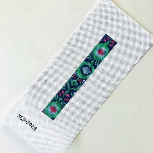 A close-up of a white woven fabric strap or band with a narrow central embroidered geometric pattern in green, blue, pink, and red, photographed on a light neutral background. Small printed text 'HCD-3024' appears near the lower left.