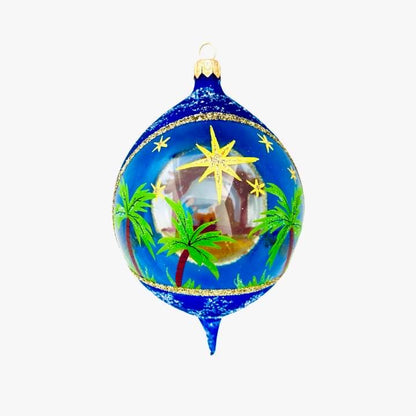 Decorative Christmas ornament with nativity scene and palm trees on a blue background