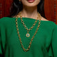 Gold chain necklace with a green gemstone pendant worn by a person in a green top.