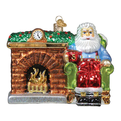 Glass ornament of Santa Claus sitting on a chair by a fireplace with a clock above.