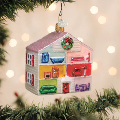 Colorful house-shaped Christmas ornament on a tree with blurred lights in the background