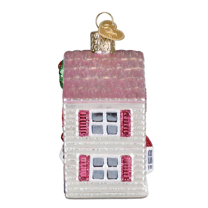 Glass house ornament with pink roof and windows on a white background
