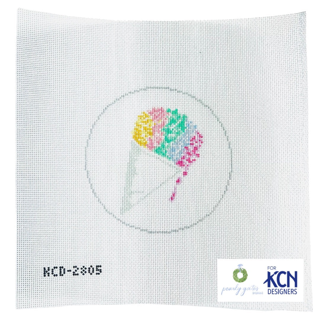Cross-stitched design on fabric with colorful abstract pattern, KCN Designers logo visible.