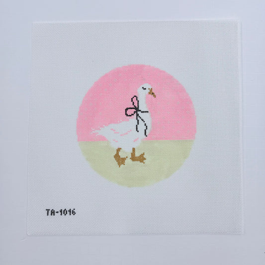 Cross-stitched design of a stork with baby shoes and socks on a pink and beige circle background.