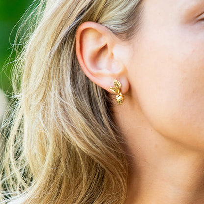 Close-up of a person wearing a gold earring with a blurred background