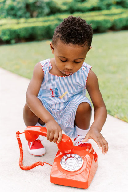 Child playing with a red toy phone outdoors