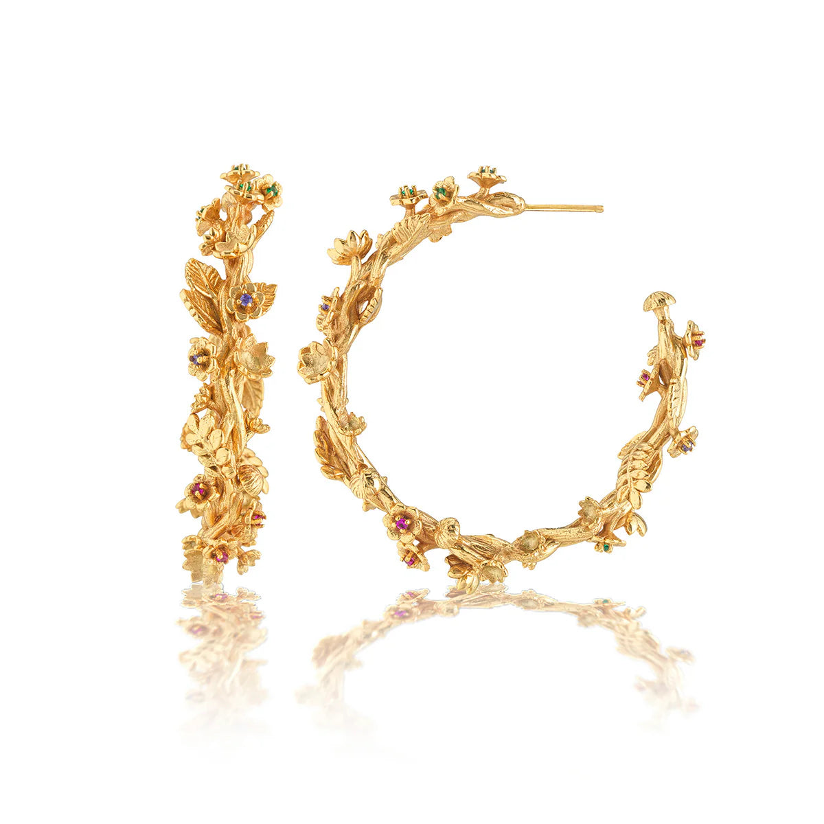 Gold hoop earrings with floral designs and gemstones on a white background
