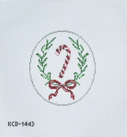 Cross-stitched design of a candy cane and bow with greenery on a light gray background.