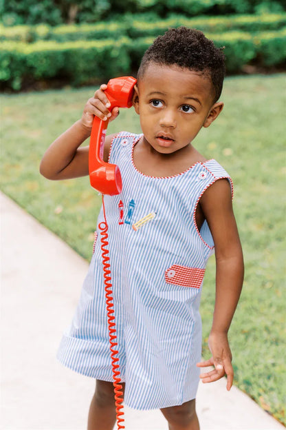 Child holding a red toy phone outdoors