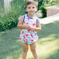 Child wearing a lobster print outfit standing on grass