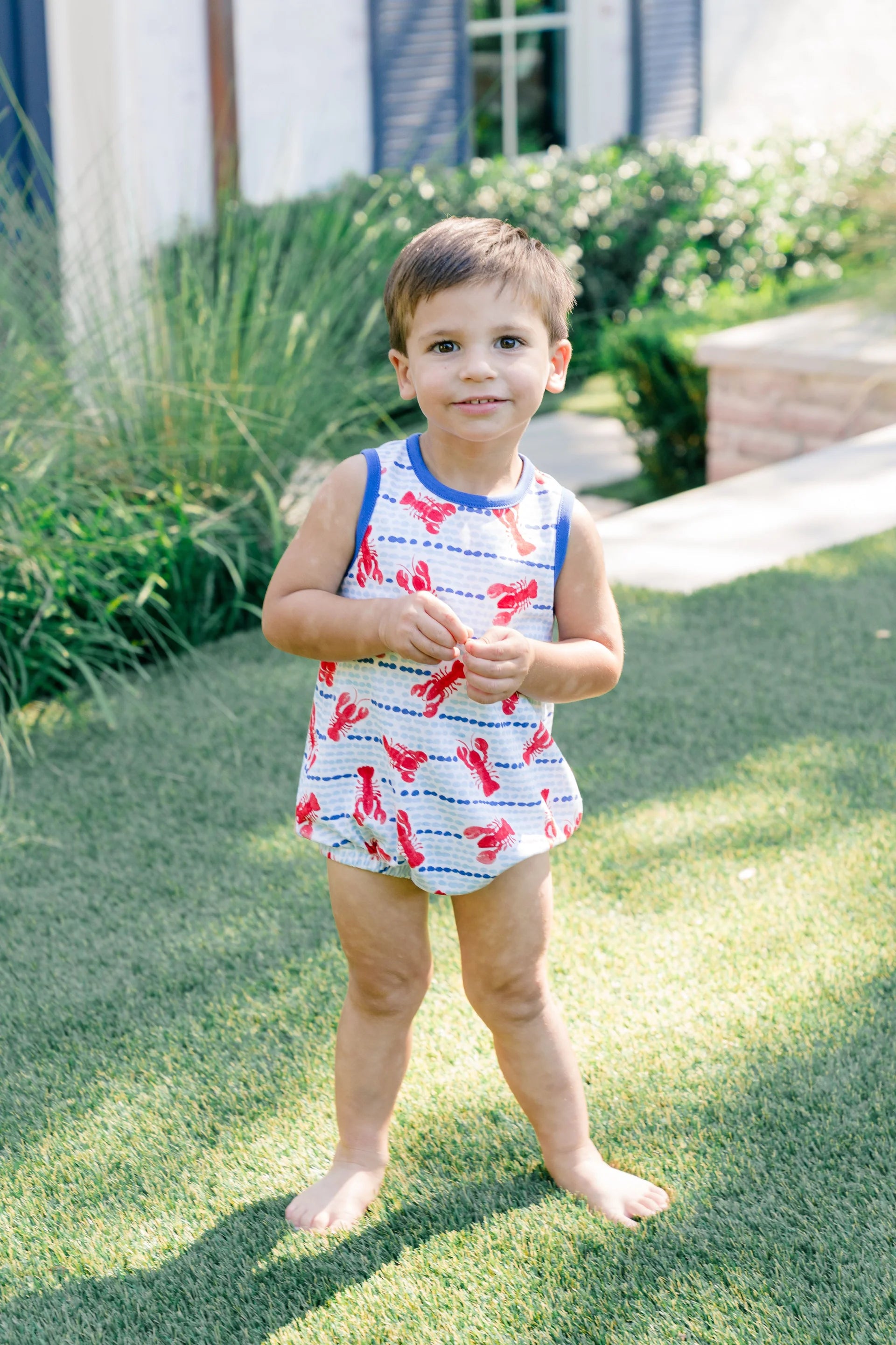 Child wearing a lobster print outfit standing on grass