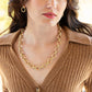 Woman wearing a gold chain necklace and earrings with a blurred background