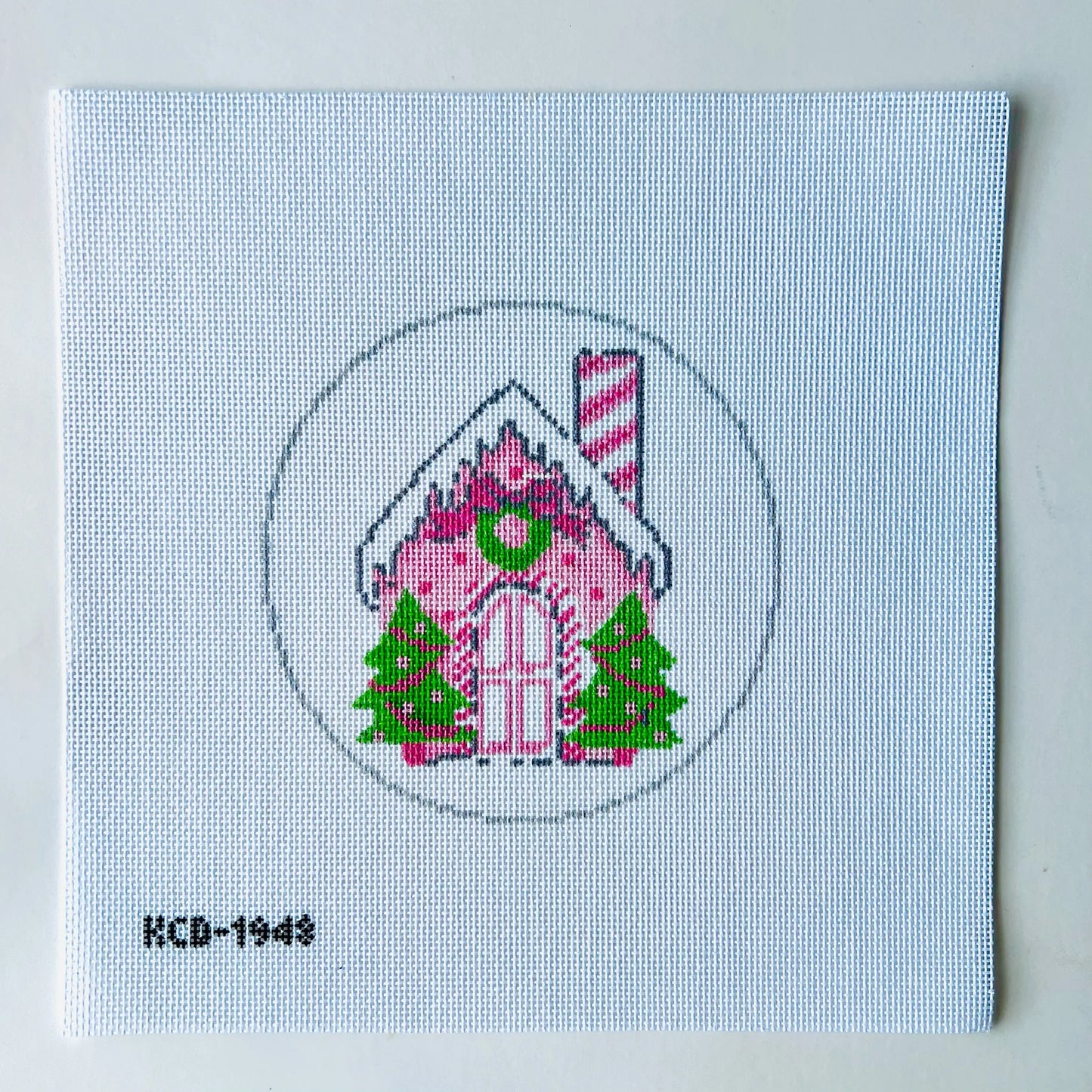Cross-stitched gingerbread house on fabric with a light blue background