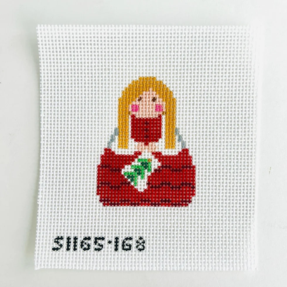 needlepoint design of a person with long blonde hair wearing a red outfit on a white background.