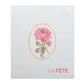 Cross-stitched design of a pink rose with a yellow border on white fabric, featuring the word 'LA FETE'.