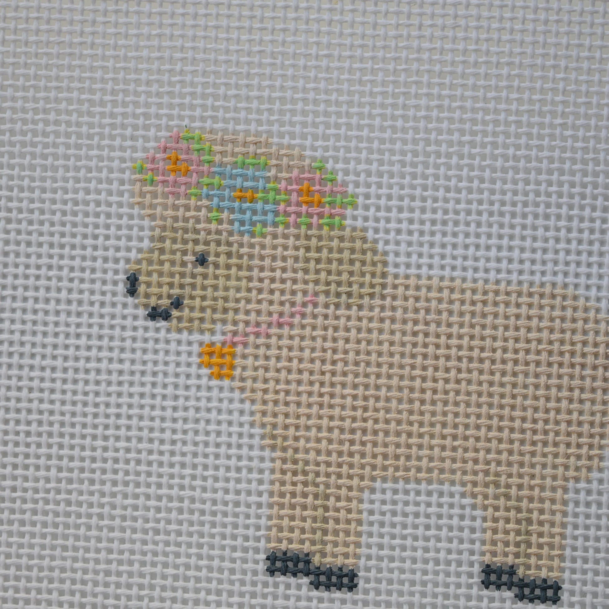 Cross-stitched sheep with a flower crown on gray fabric