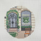 Cross-stitched design of a clog with a green pattern on a white fabric background