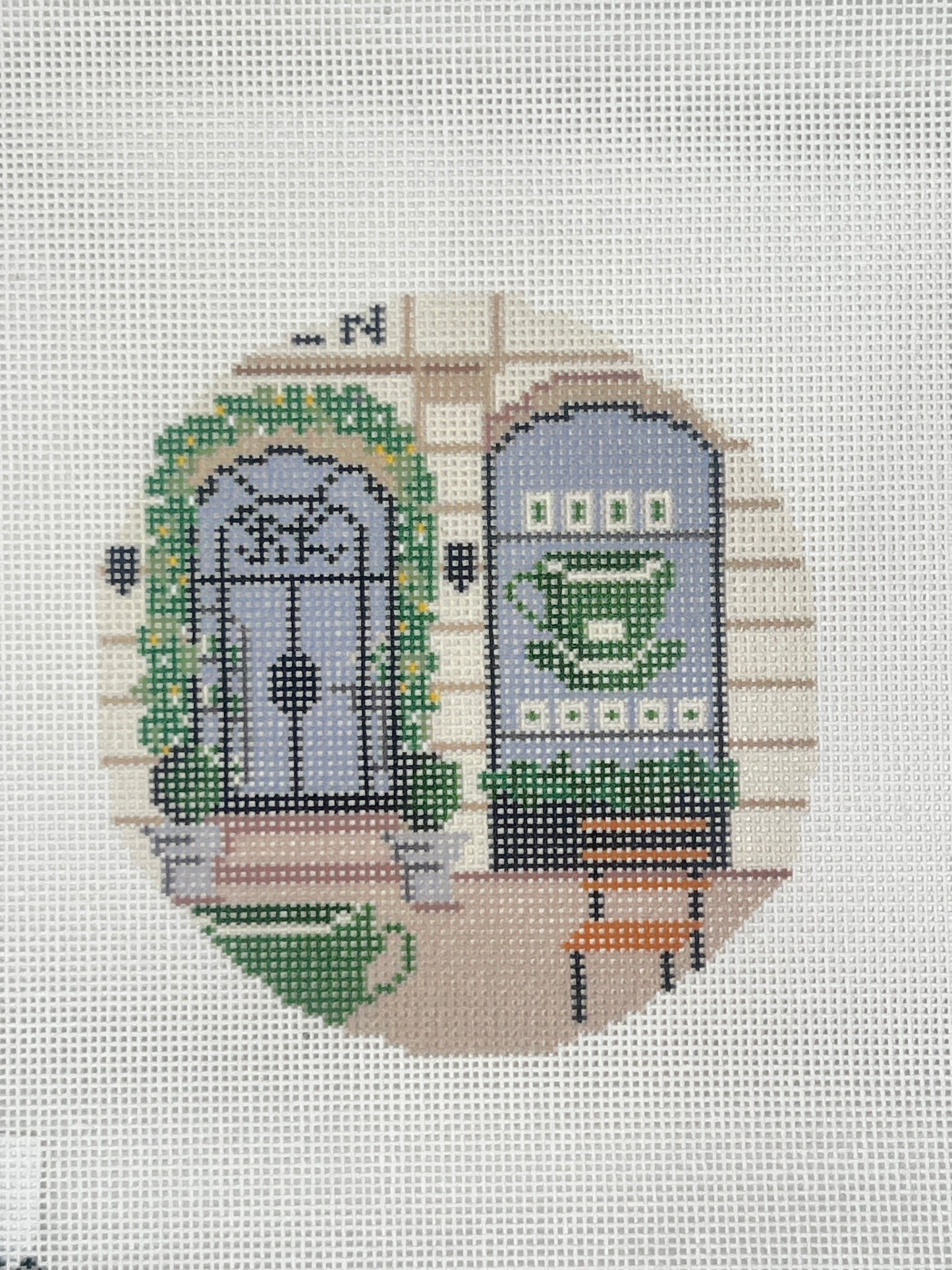 Cross-stitched design of a clog with a green pattern on a white fabric background