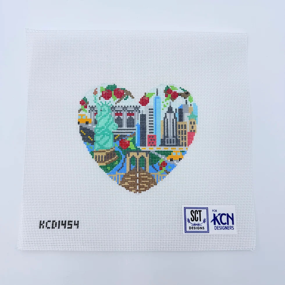 Heart-shaped cross-stitch design with city landmarks on a light blue background, featuring SCT and KCN Designs logos.