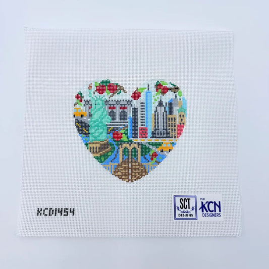 Heart-shaped cross-stitch design with city landmarks on a light blue background, featuring SCT and KCN Designs logos.