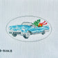 Cross-stitched design of a car with Christmas decorations on fabric.