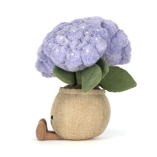 Stuffed toy resembling a purple flower in a beige pot on a white background
