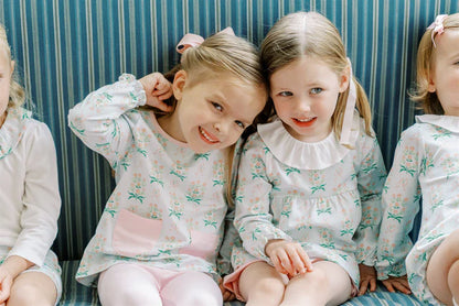 Children wearing matching pajamas sitting together against a striped background