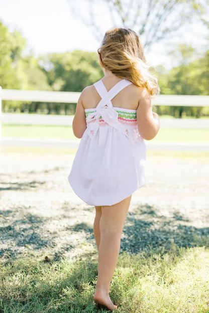 two children in white dresses hold hands outside