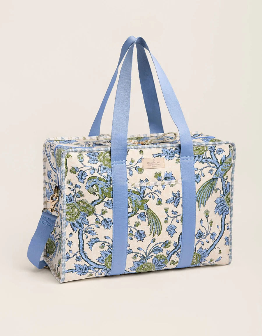 A rectangular duffel bag with a blue and green bird and floral pattern on a cream background, featuring light blue fabric handles and a matching side strap, set against a plain light beige background. Diaper Bag