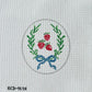 Embroidered design of a wreath with red berries and a blue bow on a white fabric background.