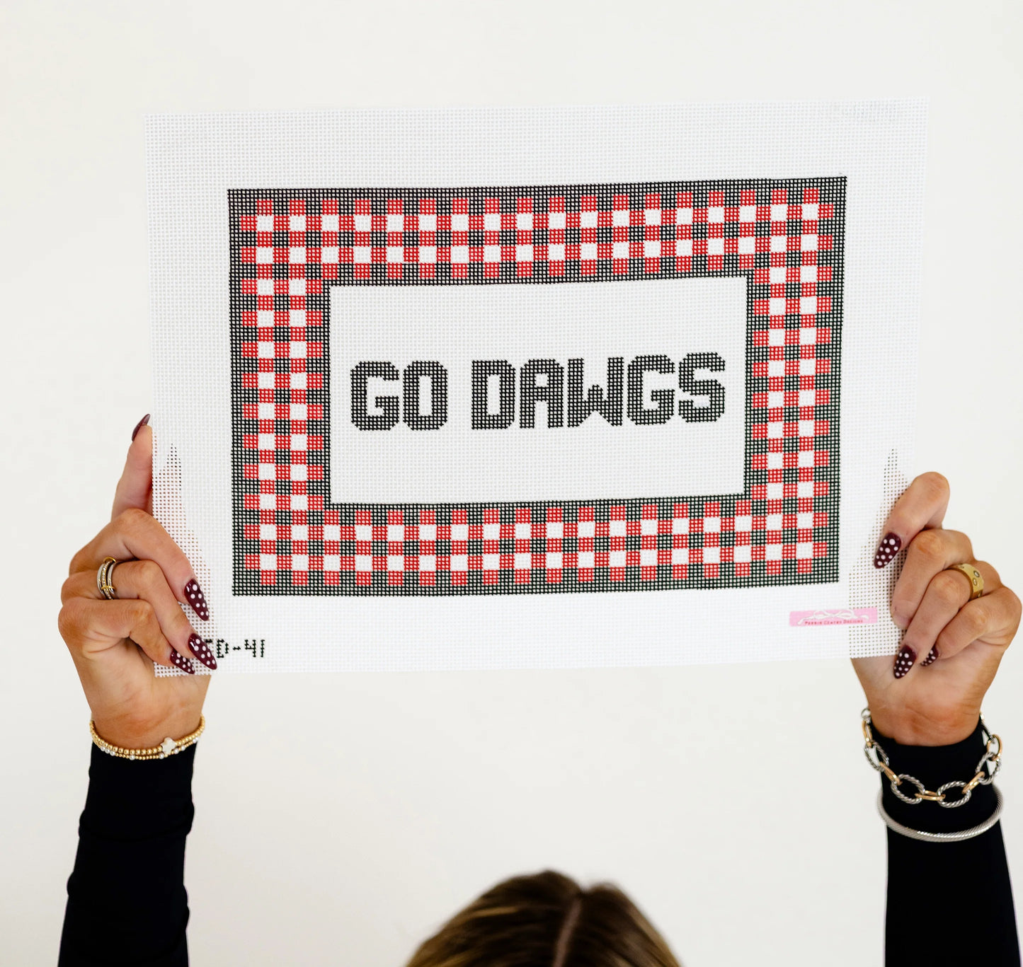 Person holding a sign with 'GO DAWGS' text and red checkered border.