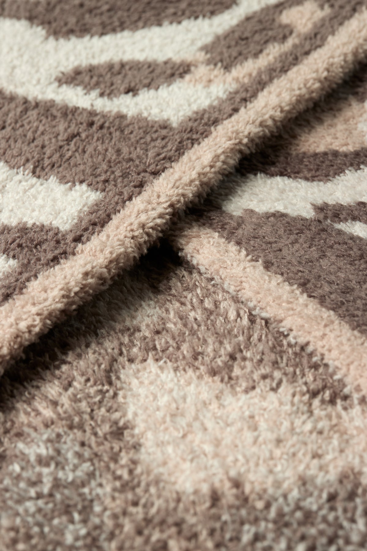 Close-up of a plush shag rug with a geometric pattern in taupe brown and cream.