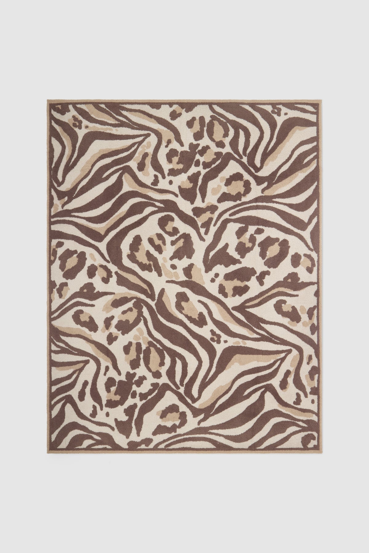 A rectangular area rug featuring an abstract zebra and leopard print pattern in shades of brown, beige, and cream, shown flat against a light gray background.