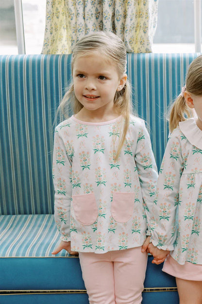 Two young girls wearing matching pajamas with a floral pattern in a room with a blue couch.