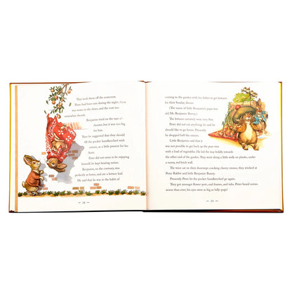 An open children's book spread showing printed text on both pages with festive holiday illustrations, including a red Santa hat, a rabbit, a Christmas tree, and a decorated ornament, photographed on a white background.