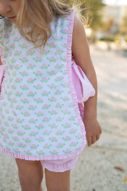 Child wearing a light blue sleeveless top with pink ruffle trim and matching shorts, standing outdoors.