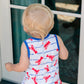 Child wearing a sleeveless shirt with red lobster print standing in front of a glass door.