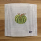 Cross-stitched green pumpkin on a white fabric background with 'SCT' branding.