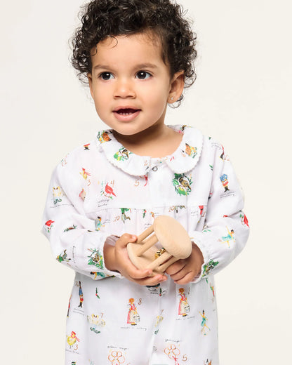 Child wearing a white outfit with colorful patterns on a plain background