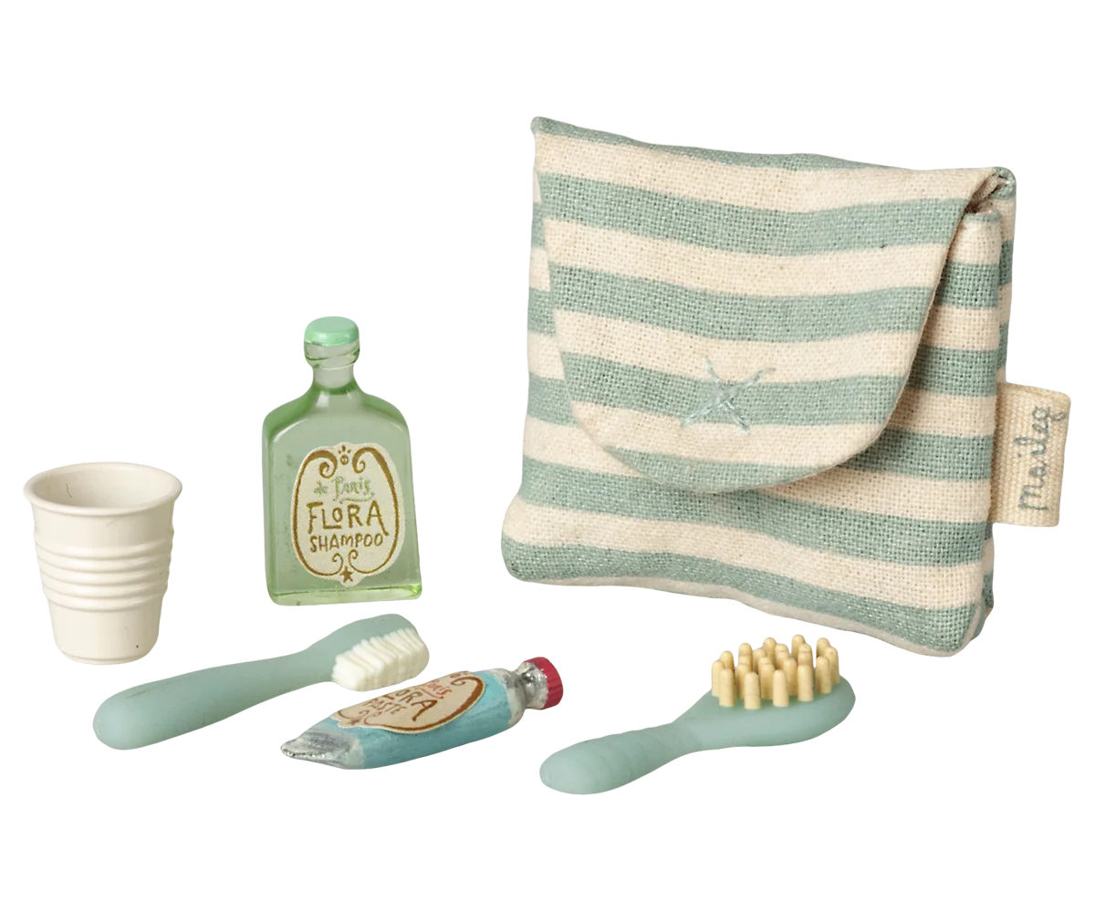Set of children's bathroom accessories including a striped pouch, cups, bottles, and brushes on a white background.