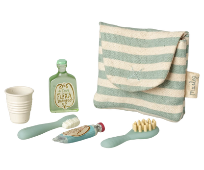 Set of children's bathroom accessories including a striped pouch, cups, bottles, and brushes on a white background.