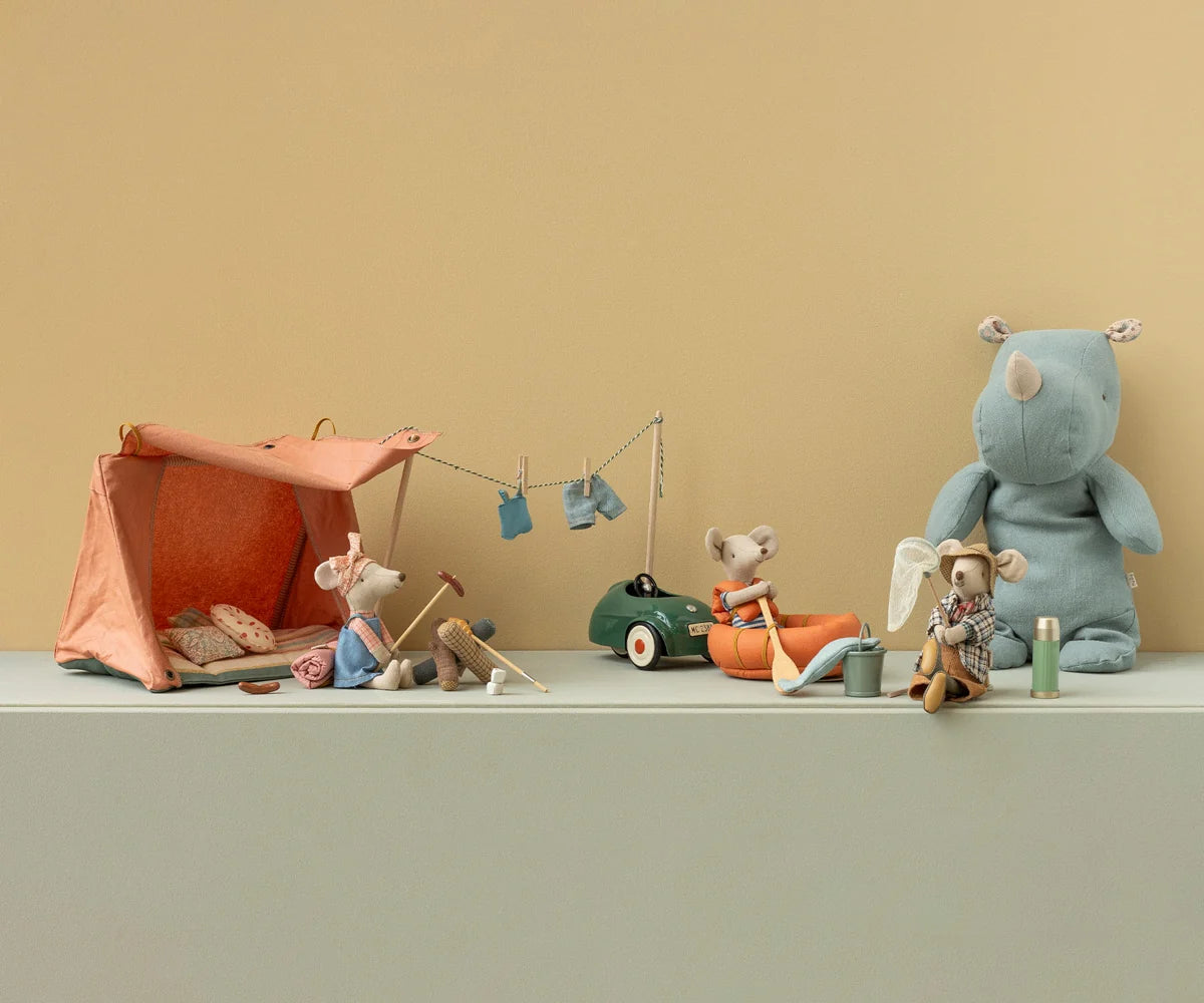 Collection of toy animals and a tent on a flat surface with a beige background