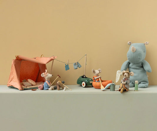 Collection of toy animals and a tent on a flat surface with a beige background