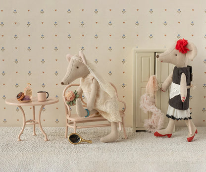 Two plush toys, one resembling a mouse and the other a cat, in a room with floral wallpaper.