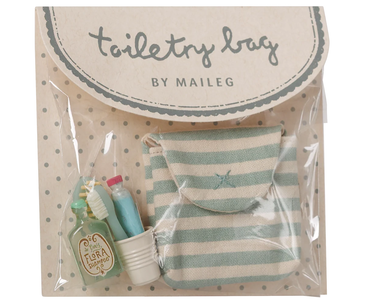 Toiletry bag set by Maileg in clear plastic packaging with a beige polka-dot backing card. The set includes a small striped mint green and cream pouch, a miniature green toiletry bottle labeled 'Tirra Loci', a small white cup, and a miniature toothbrush.