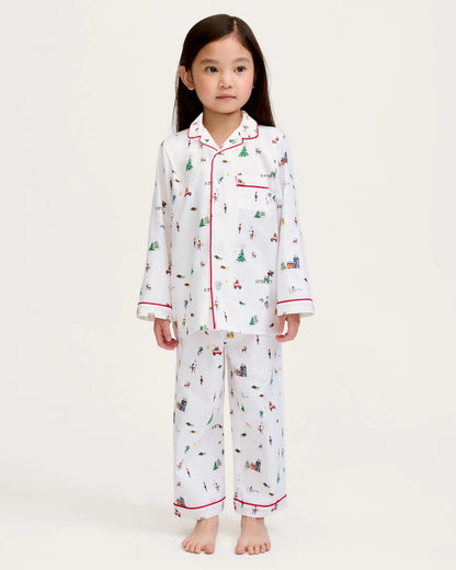 Child wearing a white pajama set with red trim on a white background