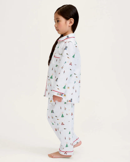 Child wearing a white pajama set with colorful patterns on a plain background